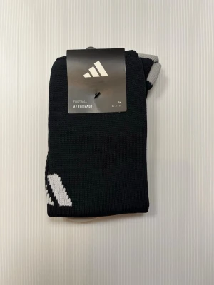 Adidas Milano 23 – fotbollsstrumpor – svarta – 37–39 – helt nya - Säljer ett par svarta fotbollsstrumpor från Adidas, modell Milano 23. Storlek EU 37–39. Helt nya – oanvända med lapparna kvar. Perfekta för match eller träning.  • Skick: Nyskick – oanvända • Storlek: EU 37–39 • Kön: Unisex / Barn / Vuxen • Färg: Svart • Märke: Adidas • Modell: Milano 23