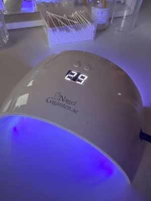 Nagelgiganten NG180 LED/UV lampa - Nagelgiganten NG180 LED/UV lampa i vit plast med digital display och timerfunktion. Lampan har en bågformad design och är perfekt för att härda gelélack och andra nagelprodukter snabbt och smidigt. !OBS! Se till att gelén du använder är kompatibel med 36W lampor innan köp! Enkel att använda och passar både hemma och i salong. Lampan köptes i julas och har blivit använd en del sen dess, men fungerar fortfarande som den ska. Allt ingår, se bilder. Kontakta mig vid frågor 💕