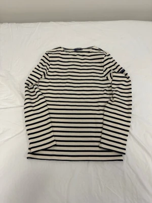 Randig långärmad topp från Saint James - Klassisk långärmad topp från Saint James i marinblått och vitt med horisontella ränder. Tillverkad i mjuk bomull och har en rak passform. Perfekt för en stilren och tidlös look.