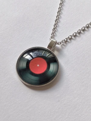 Silvrigt halsband LP-SKIVA retro mode  - Unikt halsband med ett runt hänge röd, svart LP-SKIVA I 2D Retro mode. Kedjan ankarlänk, hänget har en cool retrostil, perfekt för dig som älskar musik och vintagevibbar. Materialet rostfritt stål. (Kolla gärna in min garderob för liknande och massa andra unika smycken) 