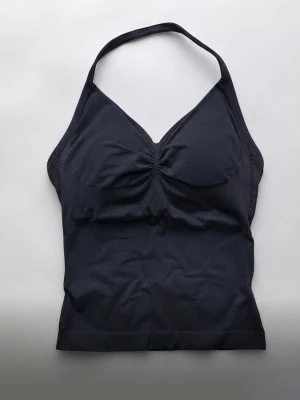 Svart halterneck linnetopp - Snygg svart linnetopp med halterneck och lätt rynkad detalj vid bysten. Toppen är ärmlös och har en figurnära passform och passar som XS-S🥰