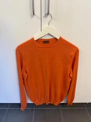 Orange stickad tröja från Stenströms i 100% Merinoull, stl M - Snygg orange stickad tröja från Stenströms med rund halsringning och långa ärmar. Tröjan har ribbade muddar vid ärmslut och nederkant. Perfekt för dig som vill ha en färgklick i garderoben.