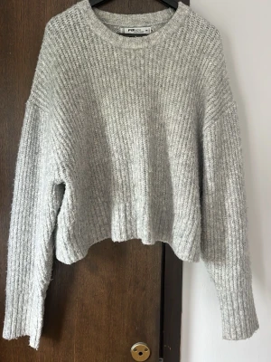 Grå ribbad stickad tröja från F&F - Mysig grå stickad tröja med ribbad struktur och avslappnad passform. Perfekt för kyliga dagar och enkel att styla med jeans eller kjol.