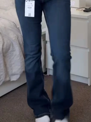 Mörkblå bootcut jeans med fickdetaljer - Snygga mörkblå bootcut jeans med dekorativa bakfickor och kontrastsömmar. Jeansen har en klassisk femficksdesign och är tillverkade i stretchigt denimtyg för en bekväm passform. 