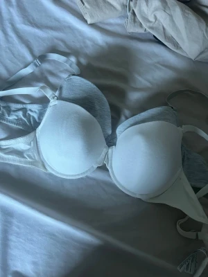  bh-ar från Primark - Säljer en vit och en grå bh från Primark med släta kupor och justerbara axelband. Bh:n har en enkel och stilren design i mjukt material, perfekt för dig som vill ha en bekväm och diskret bh under tröjan.