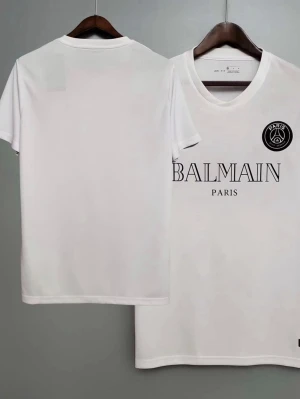 Vit Balmain Paris t-shirt - Snygg vit t-shirt från Balmain Paris med svart tryck framtill och PSG-logga på bröstet. Klassisk rund halsringning och korta ärmar. Perfekt för dig som gillar stilrena och trendiga plagg med exklusiv känsla.
