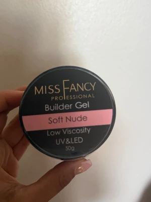 Miss Fancy Builder Gel Soft Nude - Builder Gel från Miss Fancy i färgen Soft Nude. Gelen har låg viskositet och passar för UV och LED härdning. Perfekt för att bygga naturligt snygga naglar med en mjuk nude-ton. Innehåller 50g.