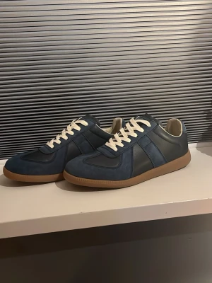 Maison margielas - Säljer ett par mörkblåa maison margiela gats med krämvita snören. Skorna är i väldigt bra skick endast använda ett fåtal gånger. 