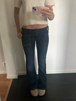 Mörkblå bootcut jeans med låg midja - Säljer ett par mörkblåa bootcut jeans. Perfekt till hösten. Använda ett par gånger men fint skick.