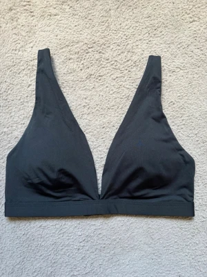 Snygg svart bikiniöverdel - Svart bikiniöverdel i trekantsmodell med djup urringning och justerbara axelband. Överdelen har hakknäppning bak och är tillverkad i ett mjukt, stretchigt material som passar perfekt för stranden eller poolen!!😍Den har vaddering som kan tas ut. Super snygg och elegant, enkel att slänga på sig💞Kan användas som bh också om man vill! Använd ca 2 gånger. Hör av vid funderingar, pris diskuterbart❤️
