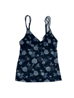 Mörkblått blommigt mesh linne - Häftigt linne i mörkblå mesh med vita och ljusblå blommor. Tunna, justerbara axelband och v-ringad halsringning. Storlek 34/36 men stretchigt material. Har dubbla tyg över bysten  för mer täckning.