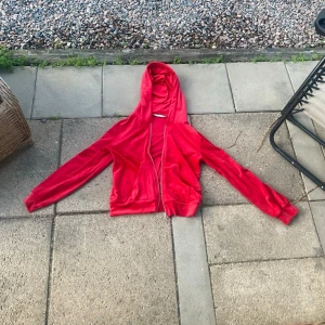 Röd velourhoodie med dragkedja - Säljer en snygg röd hoodie som slutar vid naveln och är i mjuk velour, den har dragkedja framtill och två fickor. Det är en klassisk huva och det är ribbade muddar vid ärmslut och nederkant (Se bilder). Den är från Lager157 och är i storlek Medium. Det finns 3st fläckar på baksidan som inte är så stora och som man inte ser jättetydligt (se sista bilden). Säljes pga för liten🤩☺️