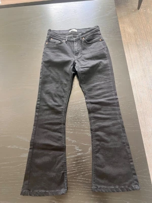 Svarta bootcut jeans - Säljer ett par svarta bootcut jeans med klassisk femficksmodell och utsvängda ben. Jeansen har normal midja och är tillverkade i ett stretchigt denimtyg för skön passform. Perfekta för dig som gillar en retroinspirerad look.