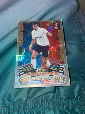Holografiskt fotbollssamlar kort - Säljer ett holografiskt fotbollssamlar kort med en mittfältare i Tottenham Hotspur tröja. Kortet har silverfärgad ram, färgglada detaljer och visar spelarens statistik. Perfekt för samlare eller fans av fotboll.