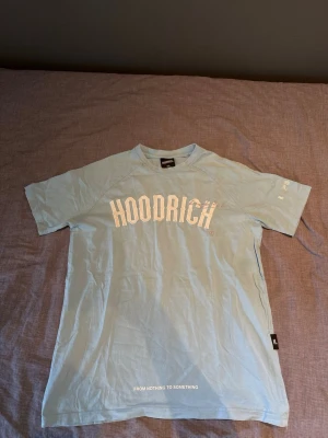Ljusblå HOODRICH t-shirt - Snygg ljusblå t-shirt från HOODRICH med vit logga framtill och tryck på ryggen. Klassisk passform med korta ärmar och rund hals. Perfekt för en avslappnad streetwear-look.