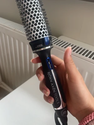 Björn Axén Tools varmluftsborste - Säljer en svart och silver varmluftsborste från Björn Axén Tools i samarbete med OBH Nordica. Borsten har rund form med vita och svarta borst, samt blå detaljer vid knapparna. Perfekt för styling av håret med integrerad värmefunktion. 30 mm