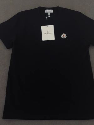 Svart Moncler t-shirt med logga - Skön svart T-shirt i strl L men passar som M. ställ gärna frågor 