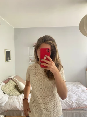 Vit/beige stickad t-shirt Comptoir des Cotonniers - Säljer en vit/beige stickad t-shirt från Comptoir des Cotonniers. Tröjan har korta ärmar, rund halsringning och ett diskret hålmönster i hela plagget. Materialet känns mjukt och luftigt, perfekt för vår och sommar.
