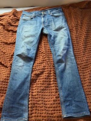 Ljusblå raka jeans med slitningar - Säljer ett par ljusblå jeans Slim fit. Jeansen har snygga slitningar och tvättade detaljer framtill och baktill. Tillverkade i denim med normal midja och knappgylf. Perfekta för en avslappnad och trendig look.