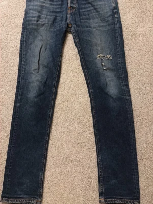 Mörkblå jeans från Nudie - Säljer ett par mörkblå jeans från Nudie med skinny fit och slitningar på höger lår. Hör av dig vid frågor☺️