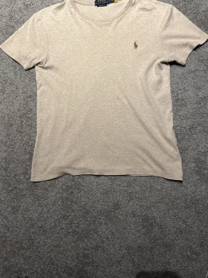 Beige t-shirt från Polo Ralph Lauren - Tjena säljer en snygg beige t-shirt från Polo Ralph Lauren. Modellen är custom slim fit. Aldrig använd bara att lappen är borttagen. T-shirten är i storlek S.  Nypris 1300kr🔥, Pris kan sänkas vid snabbaffäf 