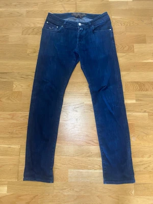 Mörkblå Replay Anbass jeans - Säljer ett par mörkblå jacob cohen jeans med klassisk femficksdesign och raka ben. Jeansen har normal passform och är tillverkade i mjukt denimtyg som ger en skön känsla. Perfekta för dig som gillar stilrena och tidlösa jeans. Köpt för 4 tusen 