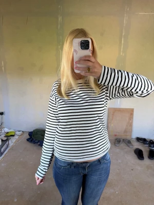 Randig långärmad tröja svart/vit - Säljer en klassisk långärmad tröja med svarta och vita horisontella ränder. Tröjan har rund halsringning och är i mjukt, tunt material som passar perfekt till jeans eller kjol. Enkel och tidlös design som alltid funkar. Den är från lindex i storlek XS och sittet fint på🩷🌸