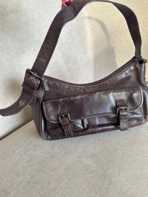 Mörkbrun axelväska i läder - Så cool vintage väska i läder. Med silvriga spännen. Lite smutsig innuti då den är vintage men går säkert att göra rent. 💗💗 lägger upp igen för fri frakt