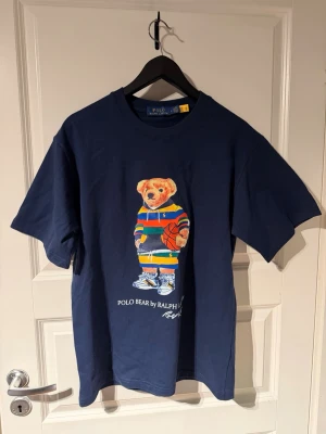 Ralph lauren T-shirt - Snygg Ralph lauren T-shirt med ett nice tryck. Jättenice material på den. Jättebra skick. Frågor? Kontakta mig✅ Allt gott, mvh Noah PS, KÖP INTE MED INSTABOX OM DU VILL FÅ VARAN FRAKTAD SNABBT‼️‼️