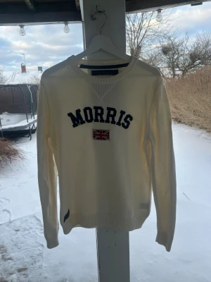 Morris Stockholm Stickad Tröja – Krämvit – Stål M - Klassisk stickad tröja från Morris Stockholm i en snygg krämvit färg. Ikoniskt broderi med logga och flagga på bröstet. • Storlek: Medium (M) • Färg: Krämvit / Off-white • Skick: fint skick , som på bilderna 🙂 • Detaljer: Ribbstickade muddar och logotyp-patch nedtill. Hör av dig vid frågor ☺️🤗 