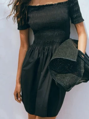 Svart offshoulder klänning - Svart klänning med offshoulder och smockad överdel, endast använd fåtal gånger