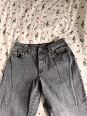 Grå Levi's 501 jeans raka ben - Säljer ett par klassiska grå Levi's 501 jeans med raka ben och fem fickor. Jeansen har knappgylf. Aldrig använda och priset är diskuterbart. Storlek W31 L32.
