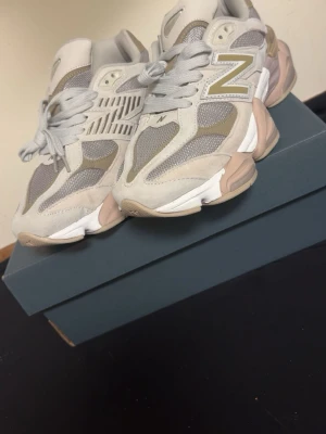 New Balance beige/grå sneakers - Snygga New Balance sneakers i beige och grå toner med mesh och mockadetaljer. Skorna har en chunky sula i vitt och beige samt den klassiska N-loggan på sidan. Perfekta för dig som gillar stilrena och trendiga sneakers med skön passform.