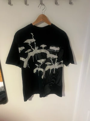 Svart Southpole t-shirt med tryck - Cool svart t-shirt från Southpole med stort vitt grafiskt tryck på framsidan. Klassisk passform och rund halsringning. Perfekt för dig som gillar streetwear och vill sticka ut med en unik design.