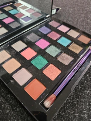 Urban Decay färgstark ögonskuggspalett - Säljer en Urban Decay ögonskuggspalett med 20 intensiva färger i både matta och skimrande nyanser. Paletten innehåller allt från nude, rosa, lila, turkos, grön till koppar och brons. Kommer med stor spegel och dubbelsidig borste i lila metall. Perfekt för kreativa sminkningar.