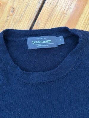 Mörkblå merinoulltröja  - Klassisk mörkblå stickad tröja från Dressmann i mjuk merinoull. Tröjan har rund halsringning, långa ärmar och ribbade muddar vid ärmslut och nederkant. Perfekt för lager på lager och enkel att matcha med olika stilar. Använd ett fåtal gånger. Nypris ca 799 kr.
