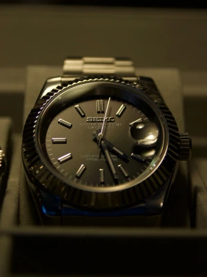 Seiko mod Datejust - Sprillans ny, jag har haft på mig den 2 dagar. 40mm med oyster armband, räfflad bezel och safir glas samt glasad baksida så man kan se urverket. Klockan har ett äkta automatiskt seiko nh35 urverk med lång kraft reserv på över 40 timmar. Timvisarna på tavlan samt tim och minut visarna lyser i mörkret. 3 extra länkar och verktyg för att sätta på / ta av länkar ingår. Kan mötas upp i Nacka om det är intressant.