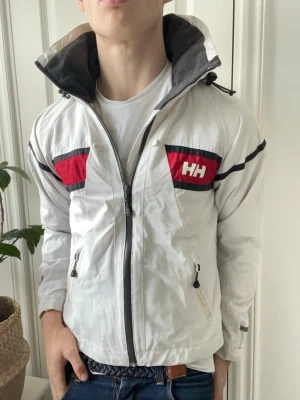 Helly Hansen vit windbreaker  - Helly Hansen vit windbreaker - lång krage, perfekt för tex skidåkning. Inga defekter! Modellen i bilderna är 180 cm 75 kg och bär Storlek S, Kom med frågor! 🌟 (Kan gå ned i pris vid köp av paket 😉) 