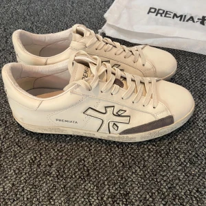 Premiata vita sneakers  - Snygga vita sneakers från Premiata i med grå detaljer och logga på sidan. Klassisk rund tå, snörning och coolt mönstrad sula. Perfekta för dig som gillar stilrena och trendiga skor. Skorna kommer med originalpåse. Självklart 100% äkta! Väldigt sparsamt använda och i toppskick! Mitt pris är 1449👍 Vid frågor/liknande är det bara att höra av sig! Återpublicerad på grund av att jag tyckte att dem var lite för stora!