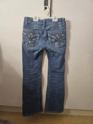 Blå jeans med broderade bakfickor från gina tricot - Snygga low-waist bootcut blå jeans från Gina Tricot i storlek 152. Jeansen har klassisk femficksdesign och coola bakfickor med broderade mönster och paljetter. I använt skick, men har inga större hål eller skador. Jättesnygga, säljer då jag redan har massa andra jeans och dessa glöms bort i garderoben. Nypris 399 kr. OBS. det finns en liten slitning på ena fickan (se bild 3), som knappt syns. 💓