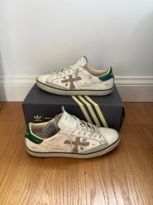 Premiata vita sneakers med gröna detaljer - Tjena 🙌 jag säljer dessa feta premiata skor. Endast skorna ingår, bra skick men har tecken på användning dock inga slitage. Skriv vid funderingar! 