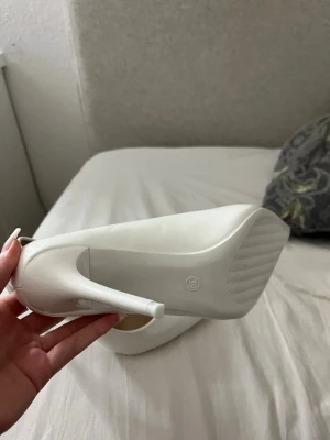 Vita pumps/ klackeskor  - Eleganta vita pumps i blank finish med spetsig tå och smal stilettklack. Perfekta till bröllop, fest, student, bal eller andra högtidliga tillfällen. Klassisk och tidlös modell som passar lika bra till klänning som till kostymbyxor.  Storlek: 39 Färg: Vit Material: Syntet med blank/lackad yta Spetsig tå Hög, smal klack i fint skick  Säljes då de inte kommer till användning. Hör gärna av dig vid frågor eller om du vill ha fler bilder