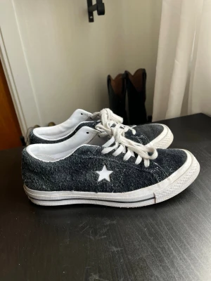 Converse One Star svarta sneakers - Säljer ett par Converse One Star sneakers i svart mocka med vit stjärna på sidan. Skorna har en klassisk låg siluett och vit sula. Insidan är vit och materialet är ruggad mocka som ger en cool och unik look. Lite anvendt 