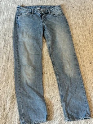 Blå low waist jeans - Säljer ett par blå low waist jeans i rakare modell. Jeansen har en klassisk ljus tvätt och är tillverkade i denim. Perfekta för en avslappnad stil och passar till det mesta. Storlek: 25/32. 