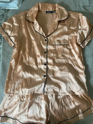 Satin pyjamasset shorts och T-shirt - T-shirt och shorts sovset. Settet är mer rosa i verkligheten. Svarta detaljer. Har använts en gång.