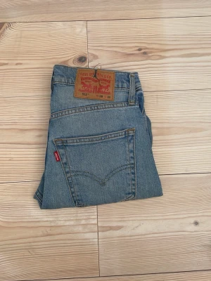 Levi's 512 blå jeans straight fit - Klassiska blå Levi's 512 jeans med straight fit och hög midja. Jeansen har fem fickor, bälteshällor och den ikoniska röda Levi's-lappen på bakfickan. Tillverkade i slitstark denim med vintagekänsla och läderpatch bak i midjan.
