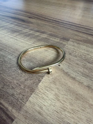 Guldigt armband i spikdesign - Snyggt armband i guldfärgad metall med unik spikformad design. Armbandet har en stilren och modern look som sticker ut och passar perfekt för dig som gillar trendiga accessoarer. Lätt att öppna och stänga tack vare smart lås.