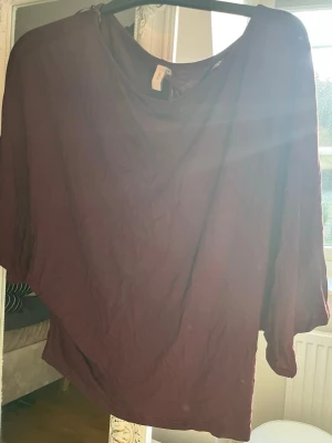 Vinröd topp från Nelly - Säljer en vinröd topp från Nelly med lös passform och rund halsringning. Toppen har trekvartsärm och är tillverkad i ett mjukt material som känns skönt mot huden. Perfekt att styla med jeans eller kjol för en avslappnad look.