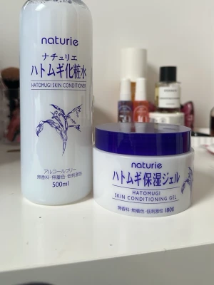 Naturie Hatomugi Skin Conditioner - Fräsch toner från Naturie i en vit plastflaska med blå text och växtmotiv. Innehåller 500 ml och är parfymfri. Perfekt för att återfukta huden och förbereda inför resten av hudvårdsrutinen. Enkel att använda och absorberas snabbt. Priset gäller för båda tillsammans.
