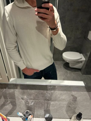 Vit Kashmir hoodie  - Säljer en riktigt snygg vit hoodie från Oscar Jacobsson. Den är i riktigt bra skick. Jag på bilden är 188cm och den är ganska kort på mig. Hör av er vid fler frågor;)